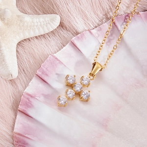 Dettaglio di una collana a croce dorata con sei zirconi su una conchiglia decorativa