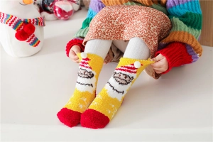 Detail of warm coral fleece Christmas socks featuring cartoon patterns and soft pompoms
