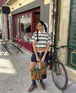 Dettaglio di un polo crop top retrò a righe verdi e gonna a pieghe blu scuro