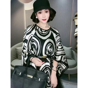Details eines eleganten schwarz-weißen Poncho-Schals mit Gürtel und Sonnenhut gestylt