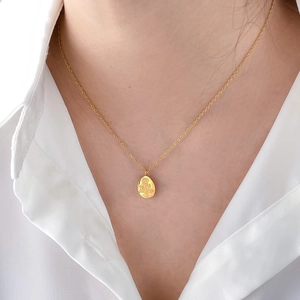 Detailed macro view of an oval rose embossed pendant on a fine gold cross chain necklace