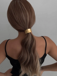 Detail of elegant gold arc ponytail cuff holder styled on model with brunette hair