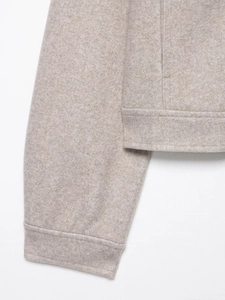 Detailed macro view of oatmeal soft wool jacket cuffs and hem with rich texture