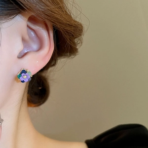 Close-up of a model wearing colorful flower stud earrings with purple and blue petals