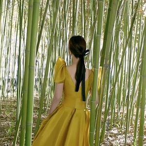 Elegant yellow satin evening dress with puff sleeves and black velvet bow hair accessory
