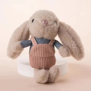 Detail of plush beige long-eared rabbit doll wearing pink striped overalls and blue shirt