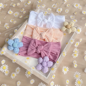 Detail view of three soft nylon baby headbands with bow knots on a floral background