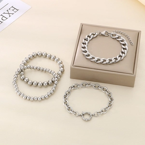 Detailed view of a four-piece silver stainless steel stacked bracelet set with Cuban chains
