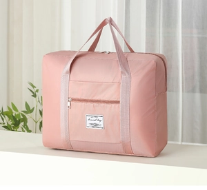 Detail of a large pink travel bag with waterproof nylon texture and sturdy handles