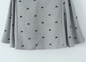Close-up of light gray fabric texture with black butterfly embroidery on dress