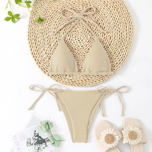 Flat lay of beige ribbed triangle bikini with neck straps and side-tie bottom on straw mat