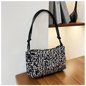 Detail of sequin shoulder bag showing the shiny texture and knotted strap design