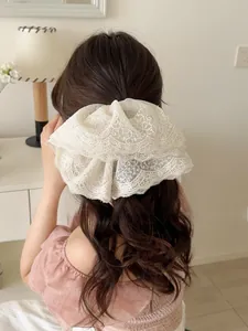 Detail of white embroidered double-layer lace bow hair clip worn in a half-up hairstyle