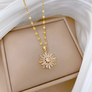 Detailed view of a gold snowflake pendant necklace with white zircons on a beige jewelry box