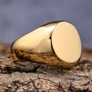 Minimalist gold-plated round signet ring with high-polished finish on rustic wood