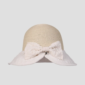 Detail of summer straw sun hat featuring a large fabric bow and woven texture