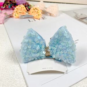 Detailed view of a blue sequined mermaid bow hair clip with a golden glitter center