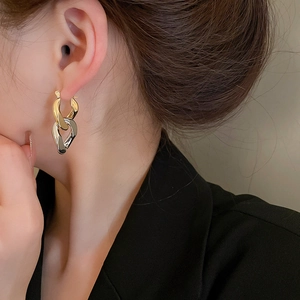 Détail de boucles d'oreilles bicolores dorées et argentées portées par un modèle