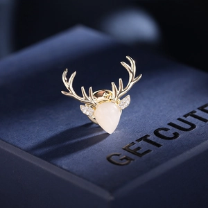 Close-up of a golden deer brooch with cat eye stone and zircon details on a gift box