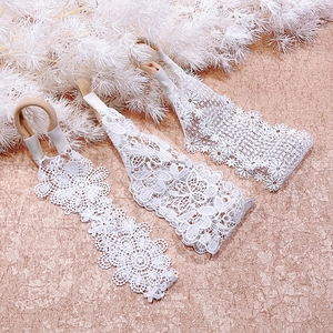Detailed view of three white lace baby headbands with delicate floral embroidery patterns