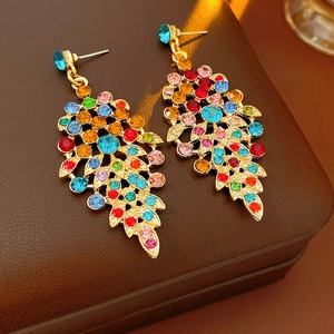 Detail of vintage gold leaf earrings with colorful rhinestones on brown leather box