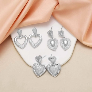 Elegant silver heart earrings with sparkling zircons displayed on soft silk fabric