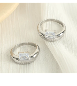 Macro shot of two silver irregular rings with square zircons on white fabric