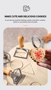 Detail of a stainless steel cookie mold with wood handle cutting heart-shaped dough