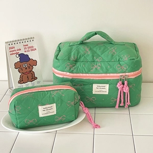 Quilted cosmetic bag set featuring green fabric with pink bow patterns and zipper details