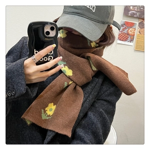 Detail of a brown knit scarf with yellow floral patterns on a heavy wool blend fabric