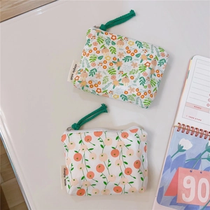 Detail of floral and fruit print cotton coin purses with woven zipper pulls on desk