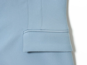 Dettaglio macro di una tasca con patta su pantaloni azzurri con cuciture rifinite