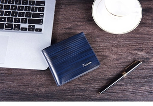 Short blue leather wallet with horizontal wood grain texture on a business office desk