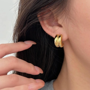 Close-up of elegant double gold arc earrings worn by a model for minimalist style