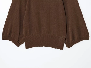 Detail of dark brown knit sweater showing ribbed cuffs and fine stitching texture