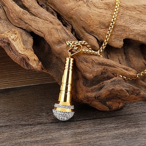 Macro shot of 18K gold microphone pendant with rhinestones on a natural driftwood base