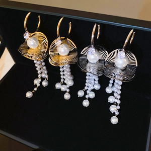 Detailed macro view of gold and silver pearl tassel earrings with zircons in a black box