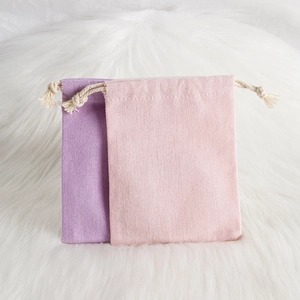 Detail of purple and pink cotton linen drawstring pouches on a soft plush background