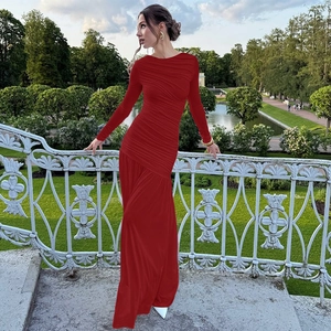 Detailansicht des roten langärmligen Plissee-Maxikleides in einem eleganten Garten