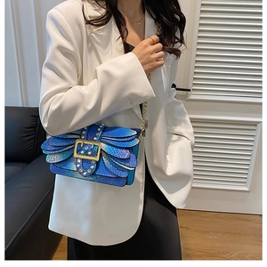 Detail of blue gradient snakeskin crossbody bag with pearls and a gold buckle