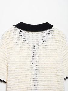 Close-up of white openwork knit top featuring a black polo collar and contrast trim