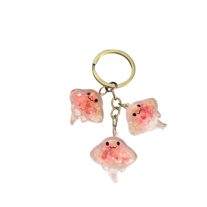 Luminous pink stingray resin keychains with glitter and gold metal rings on white background