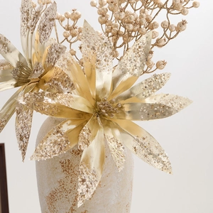 Golden artificial Christmas poinsettia flowers with glitter berries in a rustic vase