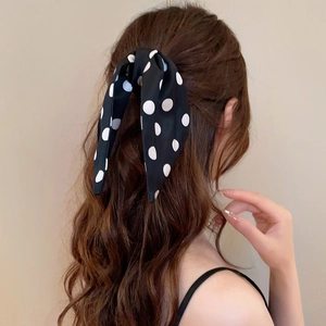 Black hair claw with white polka dot bow tie accessory on woman's ponytail back view