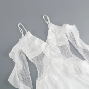 Detail of white satin dress featuring intricate lace patchwork and tiered ruffle trim