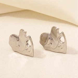 Macro shot of silver liquid-metal textured heart earrings on a beige fabric background