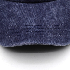 Close-up of the curved brim on a washed navy blue cotton baseball cap with stitch detail
