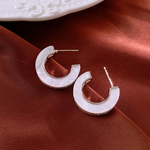 Macro shot of C-shaped marble texture hoop earrings on red silk background