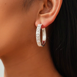 Macro shot of 18k gold plated hoop earrings with zircon flower clusters and brushed metal finish