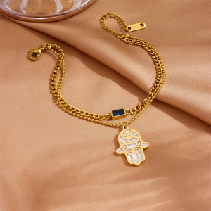 Detail of gold-plated stainless steel double-layer bracelet with Hamsa Hand and blue gem